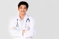 A smiling doctor posing with arms crossed on a white background is wearing a stethoscope. Young Asian doctor wearing a white coat Royalty Free Stock Photo