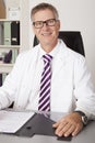 Smiling doctor sitting working at his desk Royalty Free Stock Photo