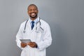 Smiling doctor standing on grey wall