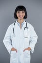 Doctor standing with hands in pocket against white background Royalty Free Stock Photo