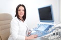 Smiling doctor using ultrasound equipment and computer. Royalty Free Stock Photo