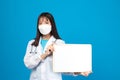 Smiling doctor wearing face mask holding blank banner or card with stethoscope on blue background Royalty Free Stock Photo