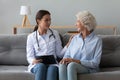 Smiling doctor consulting older woman patient during visit at home Royalty Free Stock Photo