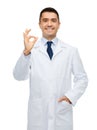 Smiling doctor in white coat showing ok hand sign