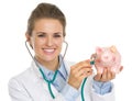 Smiling doctor woman listening piggy bank with stethoscope