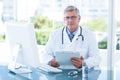 Smiling doctor working on computer at his desk Royalty Free Stock Photo