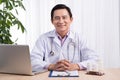 Smiling doctor working on computer at his desk Royalty Free Stock Photo