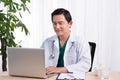 Smiling doctor working on computer at his desk Royalty Free Stock Photo