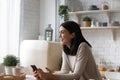 Smiling dreamy Asian woman holding smartphone, looking in distance