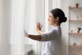 Smiling dreamy Indian woman opening curtains in early morning Royalty Free Stock Photo