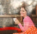 Smiling dreamy thoughtful woman in restaurant with cup of coffee, joyfully looking out, view through window with reflections Royalty Free Stock Photo