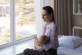 Smiling dreamy young mother breastfeeding newborn baby.