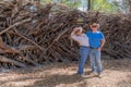 Smiling Dutch tourist couple against fence made of tree branches and wooden posts in public park