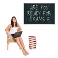 Smiling elder schoolgirl or young student with a huge pile of books and a laptop in front of a blackboard Royalty Free Stock Photo