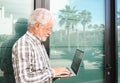 Smiling elderly businessman holding laptop computer on his hands standing out of his office. Mature attractive man wearing Royalty Free Stock Photo