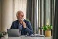 Smiling elderly businessman with laptop looking away at desk in office Royalty Free Stock Photo