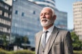 Smiling elderly entrepreneur looking away while standing against business office buildings Royalty Free Stock Photo