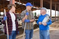 Smiling elderly farmer friendly chatting with son and grandson near stall with cows