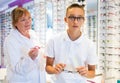 Elderly female consulting teenager in optical store