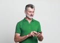 Smiling elderly gray-haired mustache bearded man Using mobile phone, typing sms message. Royalty Free Stock Photo