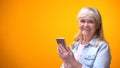 Smiling elderly lady using cellphone, easy application for retiree, social media Royalty Free Stock Photo