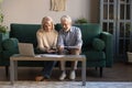 Smiling elderly spouses paying bills online using laptop