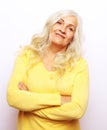 Smiling Elderly Woman With Crossed Hands Stands In Front Of White Grey Background.