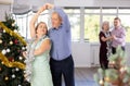 Smiling elderly woman and partner successfully perform mesmerizing movements of paso doble dance during celebration