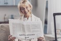 Smiling elderly woman reading info about current events