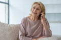 Smiling elderly woman talking on a mobile phone at home, relaxing on the sofa in the living room Royalty Free Stock Photo