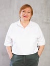 Smiling elderly woman in white shirt with hands in pockets Royalty Free Stock Photo