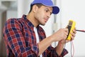 smiling electrician using multimeter on electric meter Royalty Free Stock Photo