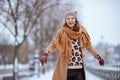 smiling elegant female in brown hat and scarf in camel coat Royalty Free Stock Photo