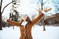 Smiling elegant female rejoicing outside in city park in winter