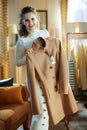 Smiling elegant housewife holding on hanger purchased new coat