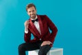 Smiling elegant man sitting and wearing red velvet tuxedo Royalty Free Stock Photo