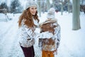 smiling elegant mother and daughter shaking snow off clothes