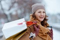 smiling elegant woman in brown hat and scarf in camel coat