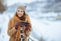 smiling elegant woman in brown hat and scarf using phone app Royalty Free Stock Photo