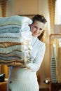 Smiling elegant woman looking out from huge pile of sweaters