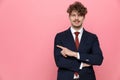 Smiling elegant young man in suit pointing finger to side Royalty Free Stock Photo