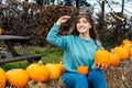 Smiling emotional young woman in witch hat holding pumpkins. Female posing while selecting best pumpkins for