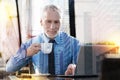 Smiling employer drinking coffee while waiting for his new employee