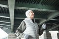 Smiling energetic senior woman jogging under bridge