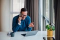 Smiling entrepreneur discussing on cellphone while using laptop at office desk Royalty Free Stock Photo