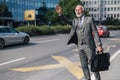 Smiling entrepreneur with laptop bag hailing for cab in the city during sunny day Royalty Free Stock Photo