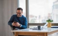 Smiling entrepreneur socializing on smart phone while working at the office desk