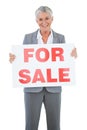 Smiling estate agent holding for sale sign