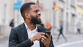 Smiling ethnic African American bearded man businessman executive employer with smartphone in city chatting shopping Royalty Free Stock Photo