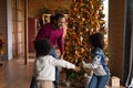 Smiling ethnic dad and children play near fir tree Royalty Free Stock Photo